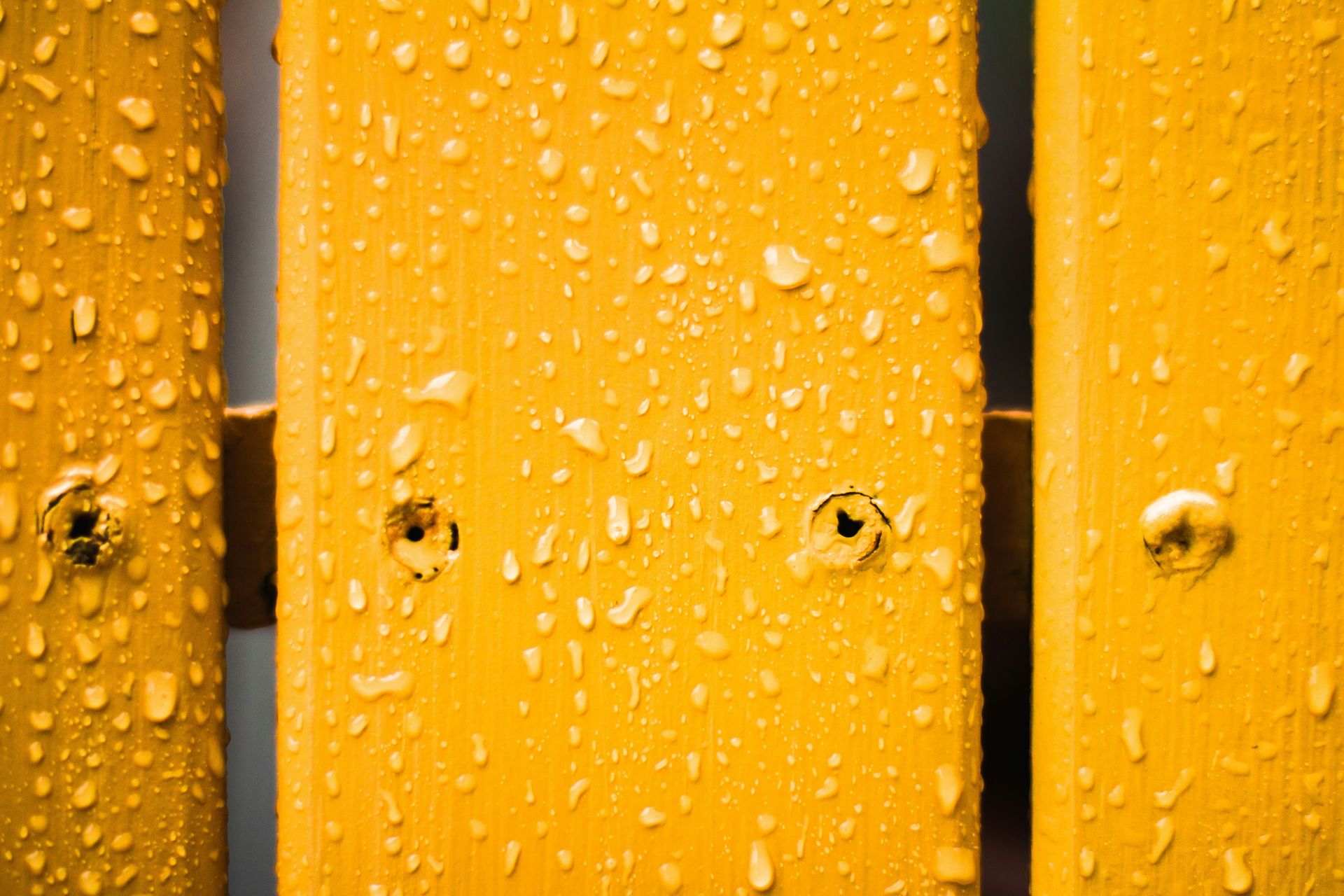a close up of water droplets on a yellow fence
